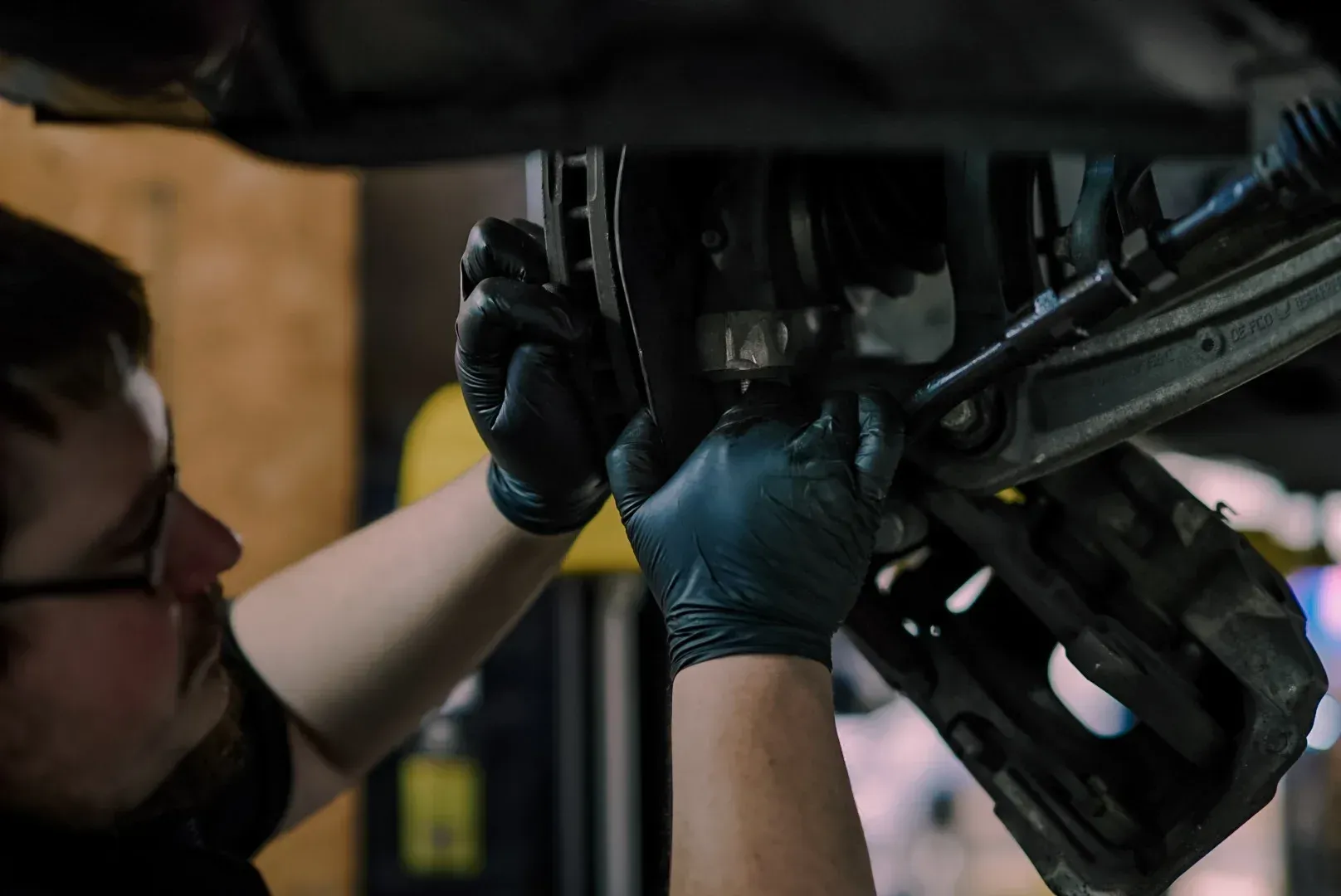 Person holding a car axle with brake rotors attached in a dim garage
