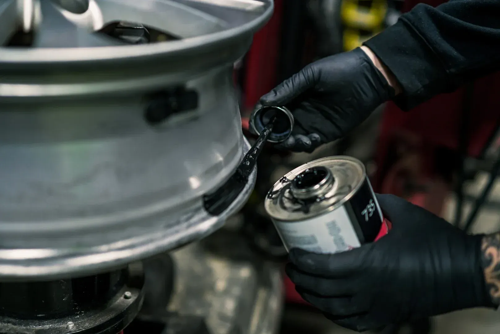 Mechanic tightening a wheel rim on a vehicle tire with a hand tool