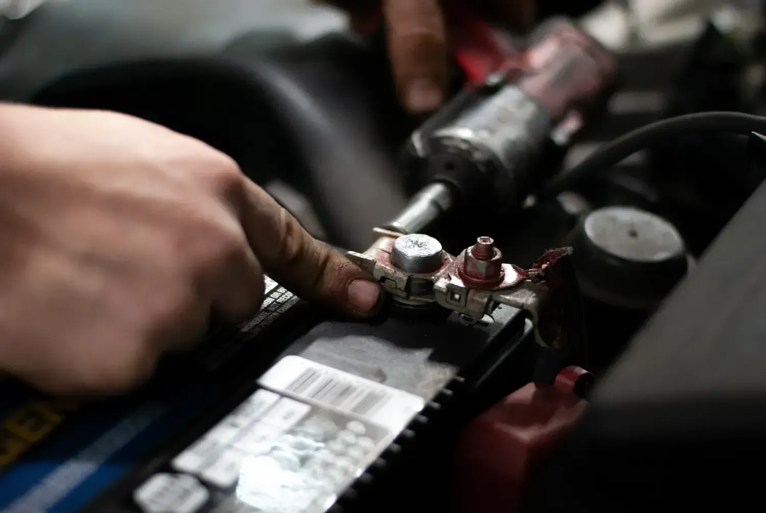 Hand placing a car battery into a vehicle engine compartment