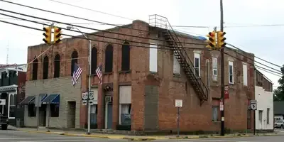 Corner brick building with fire escapes, American flags, and traffic lights at an intersection
