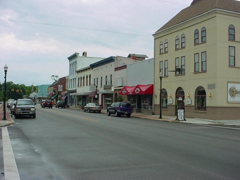 Aerial view of a small town with streets, buildings, and scattered trees under a cloudy sky