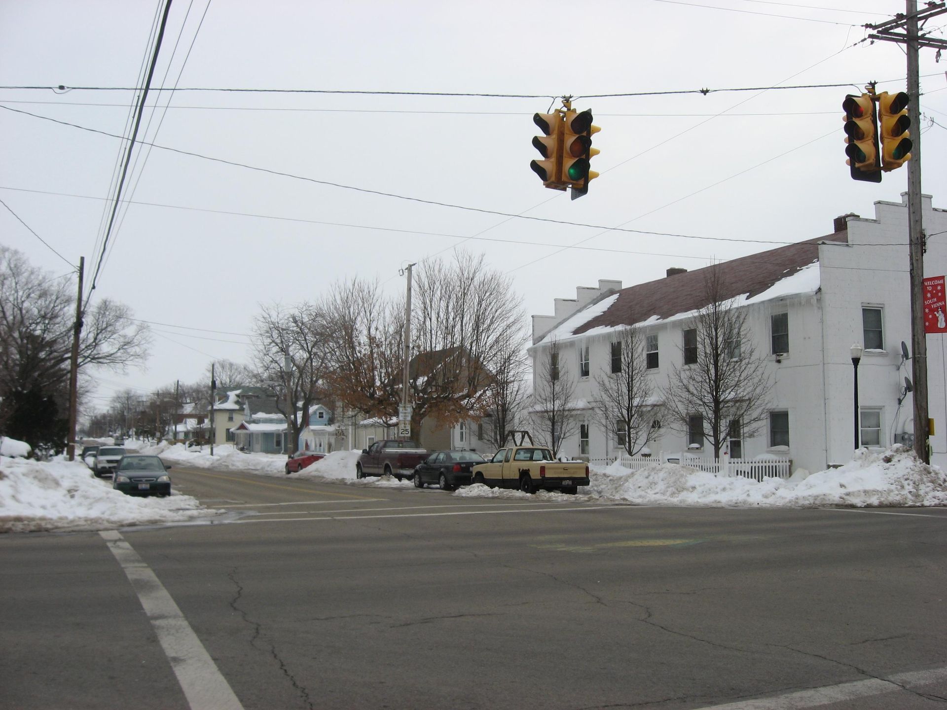 Corner brick building with fire escapes, American flags, and traffic lights at an intersection