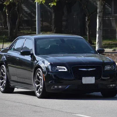 Black sedan driving on a sunlit street near palm trees