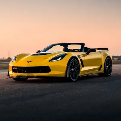 Yellow convertible sports car parked on an empty road at sunset