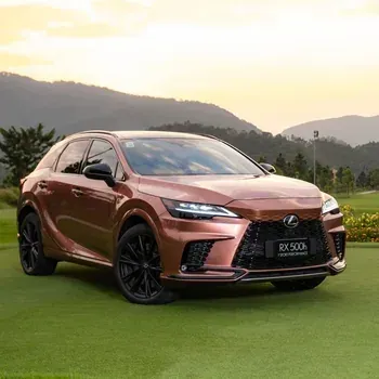 Copper Lexus RX 500h SUV parked on grass at sunset with mountains in the background
