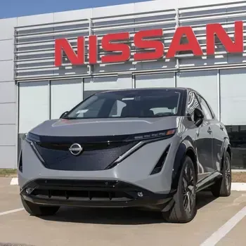 Gray Nissan SUV parked outside a Nissan dealership under a red sign