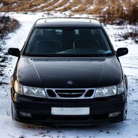 Black sedan parked on a snowy rural road, front view