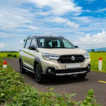Silver Suzuki SUV parked on a rural road under a blue, cloudy sky