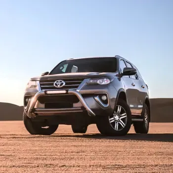 Silver Toyota SUV driving on a sandy desert under a clear blue sky.