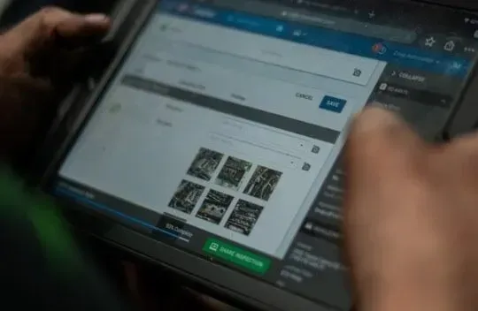 Zima mechanic using a tablet with a photo gallery open in a web browser