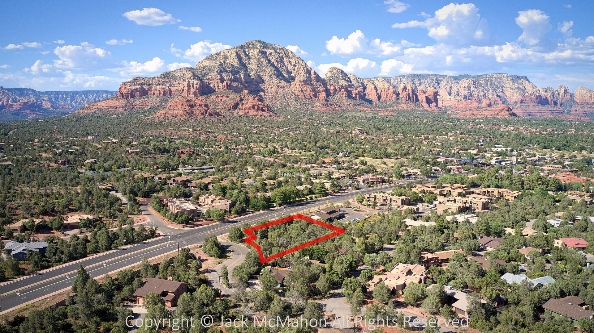 Aerial view of a town in Arizona with red rock mountains in the background. A red box highlights a vacant lot.