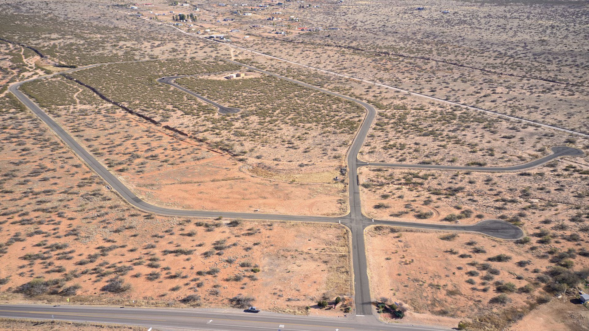 Aerial view of desert landscape with intersecting roads and sparse vegetation.