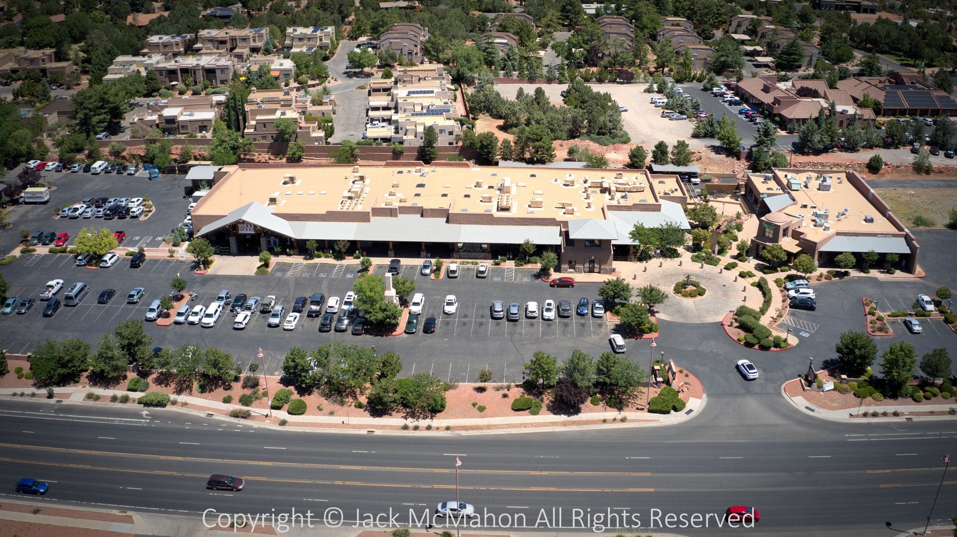 Aerial view of a commercial building with a large parking lot and surrounding residential area.