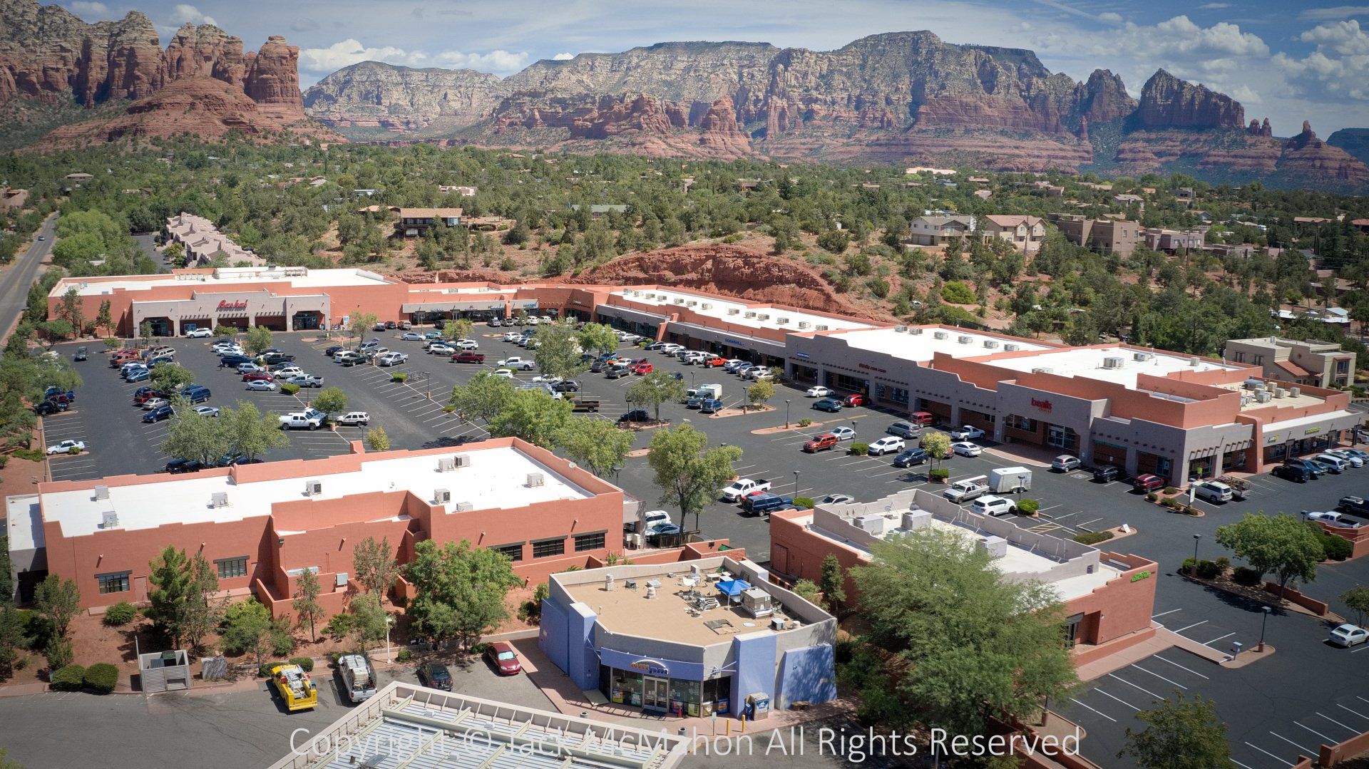 Aerial view of a shopping center in Sedona, Arizona, with red rock formations in the background.
