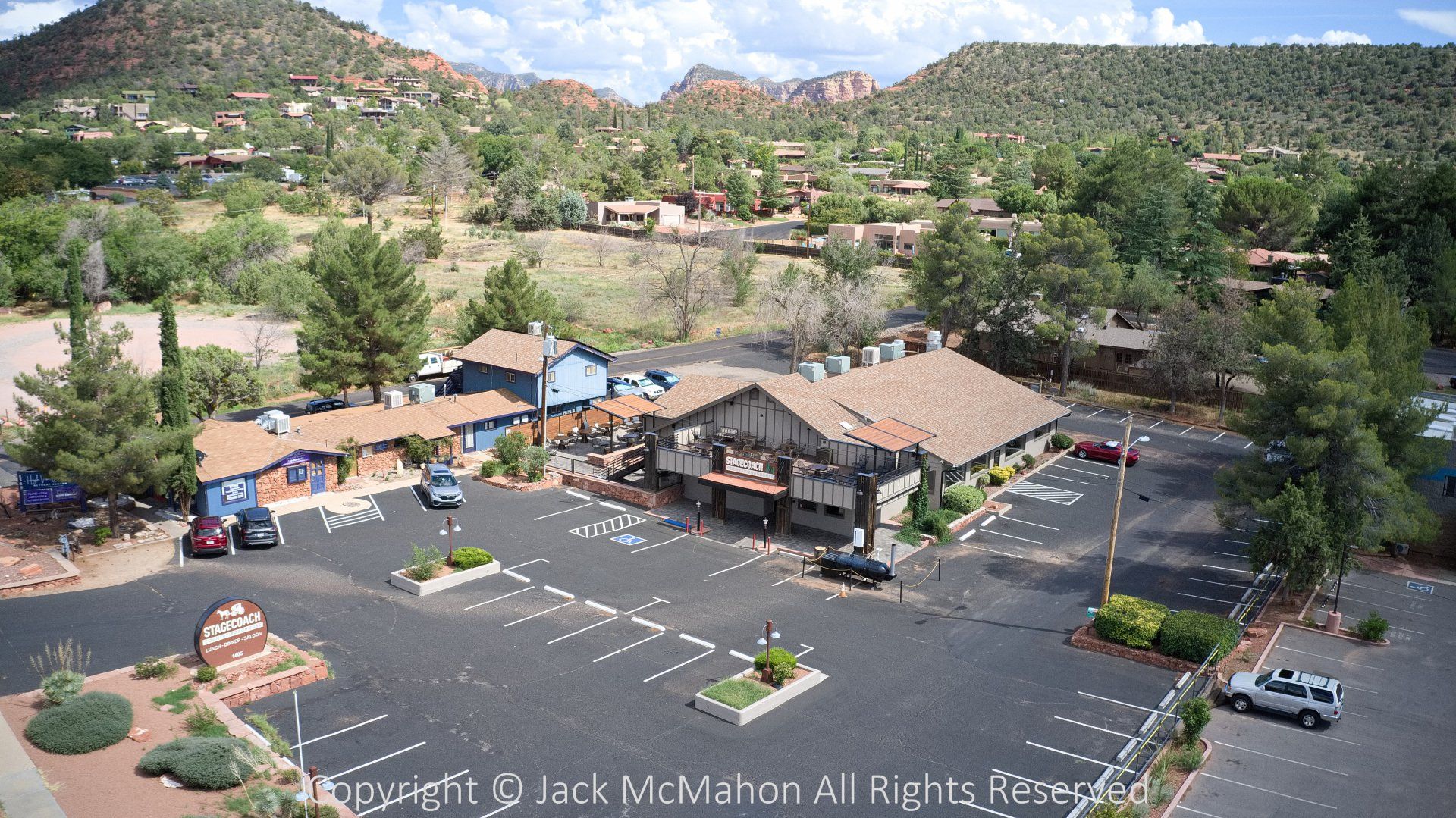 Aerial view of a parking lot, buildings, and red rock mountains in Sedona, Arizona.