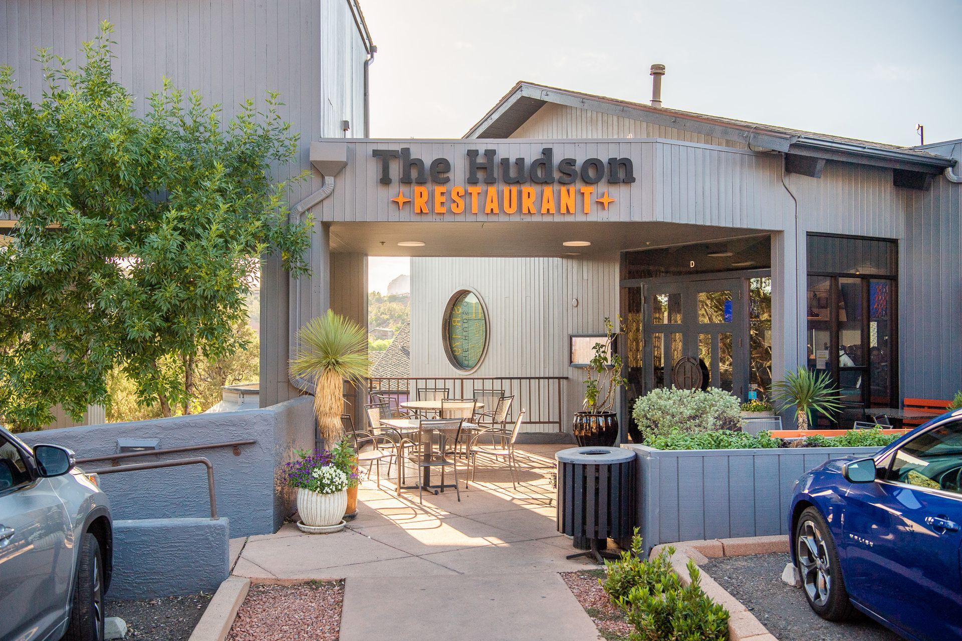 Exterior view of The Hudson Restaurant with patio seating and a parking area.