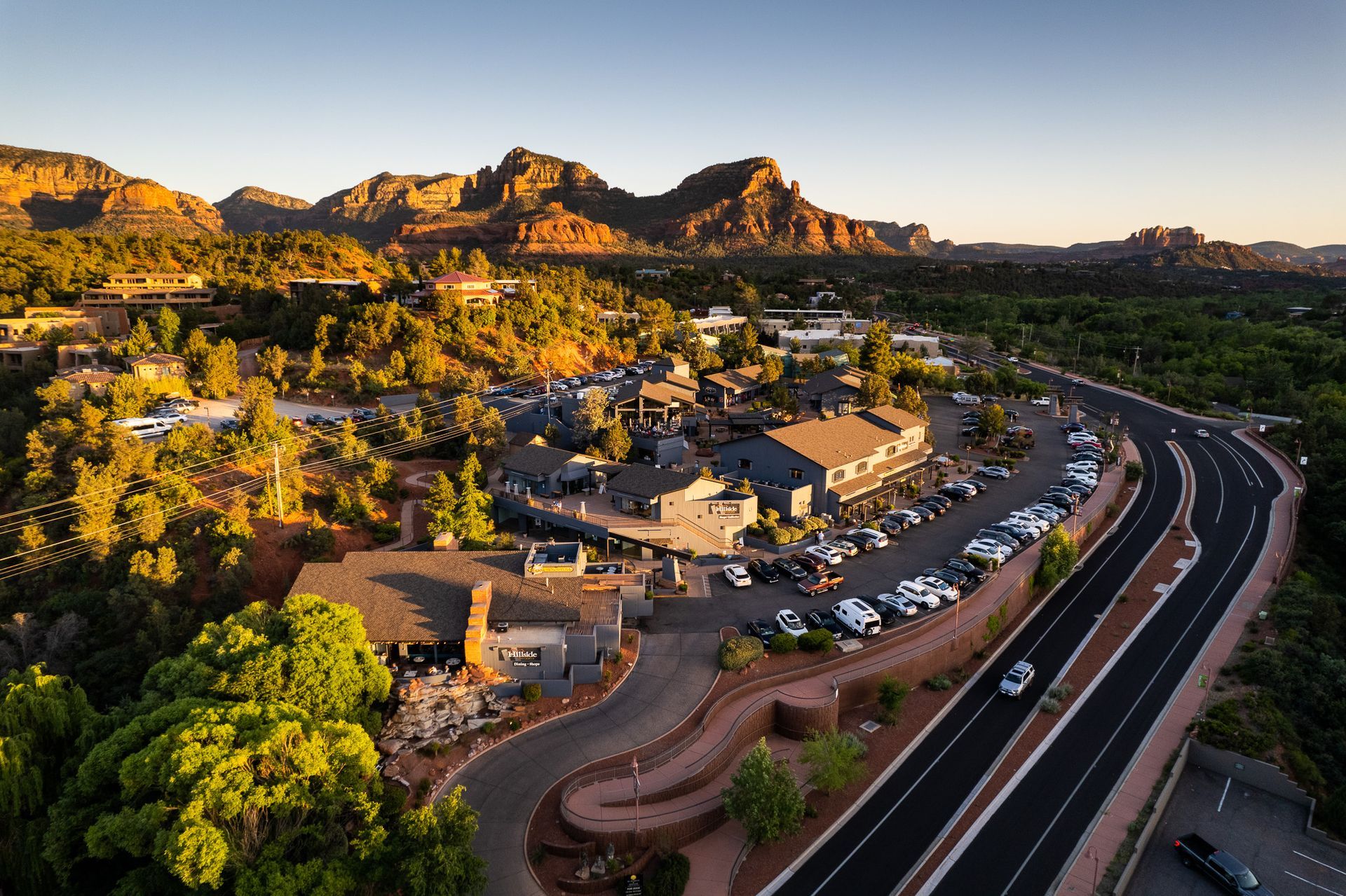 Aerial view of Sedona, Arizona, featuring buildings, a road, and red rock mountains.