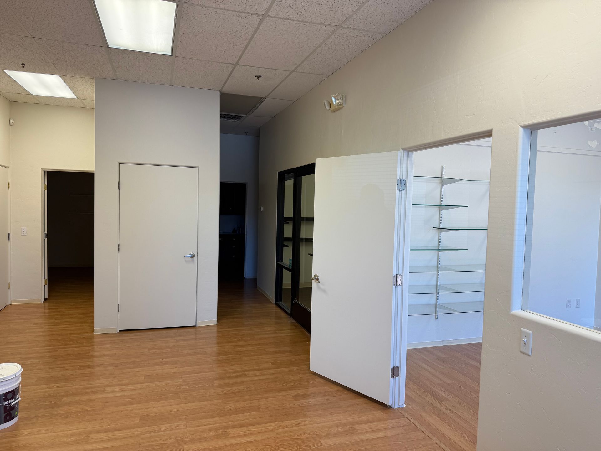 Empty office interior with wood-look flooring, white walls, and open doorways.