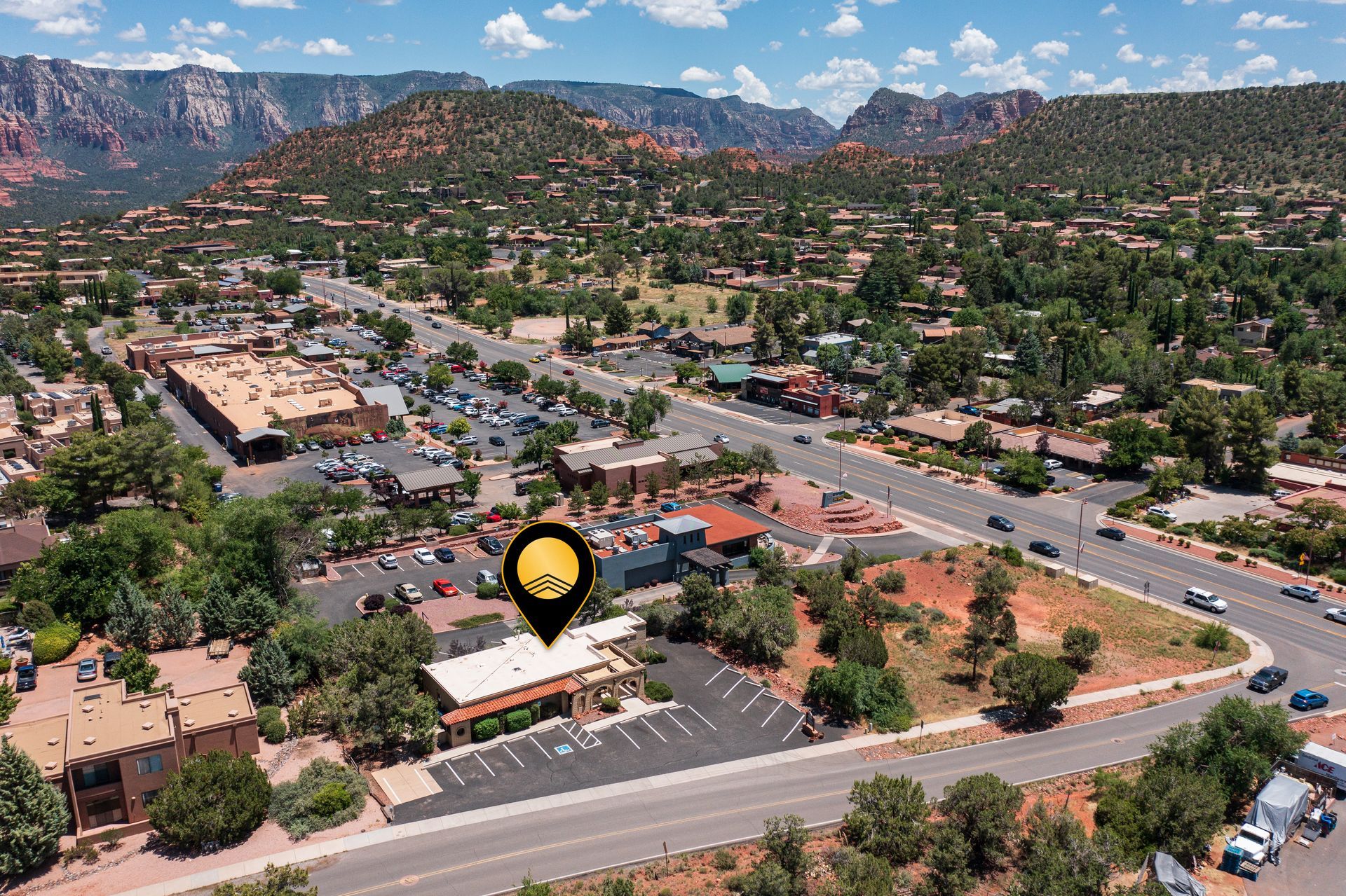 Aerial view of Sedona, Arizona, with a restaurant marked by a location pin; red rock formations in background.