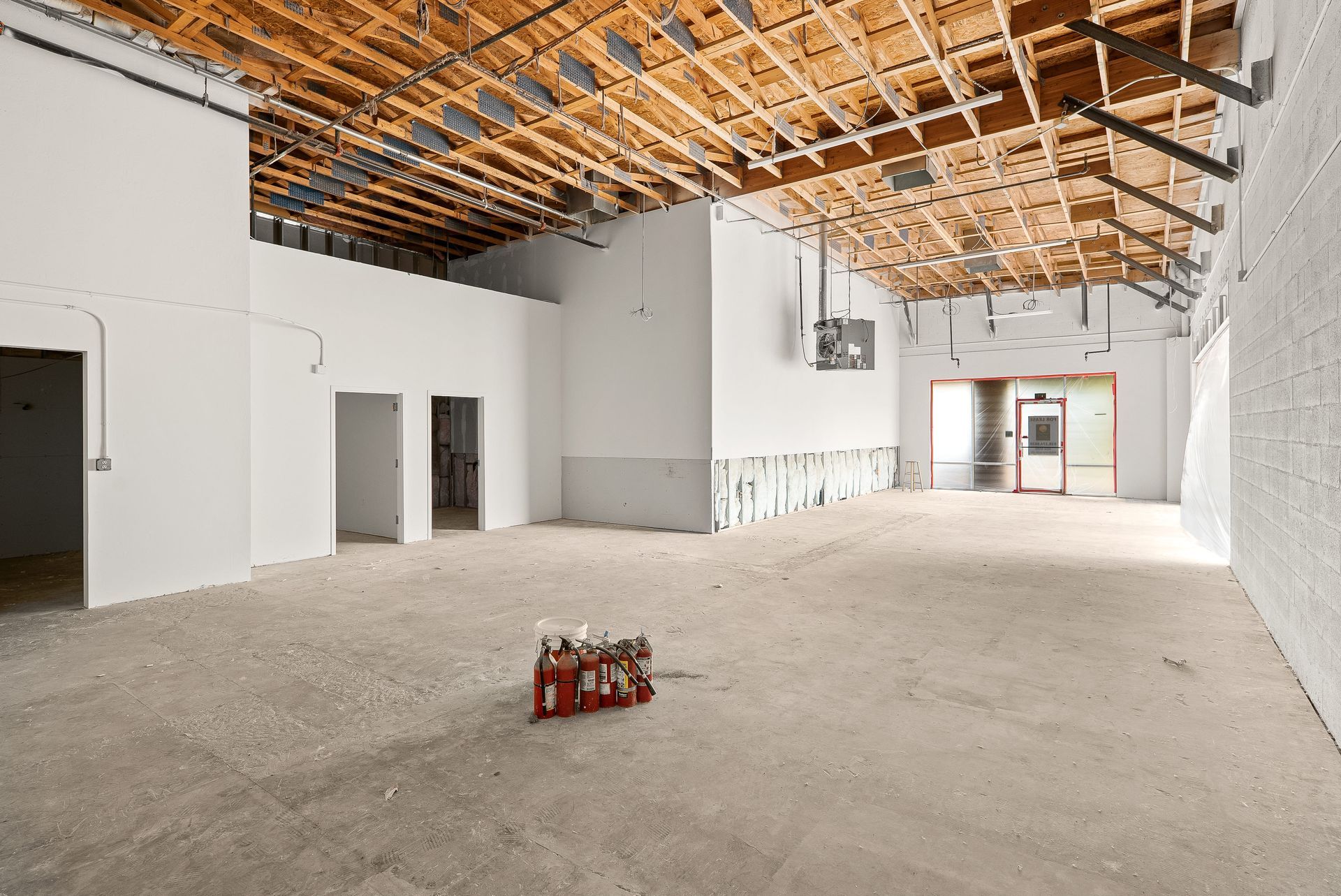 Interior of a building under construction, showing exposed beams, unfinished walls, and concrete floor.