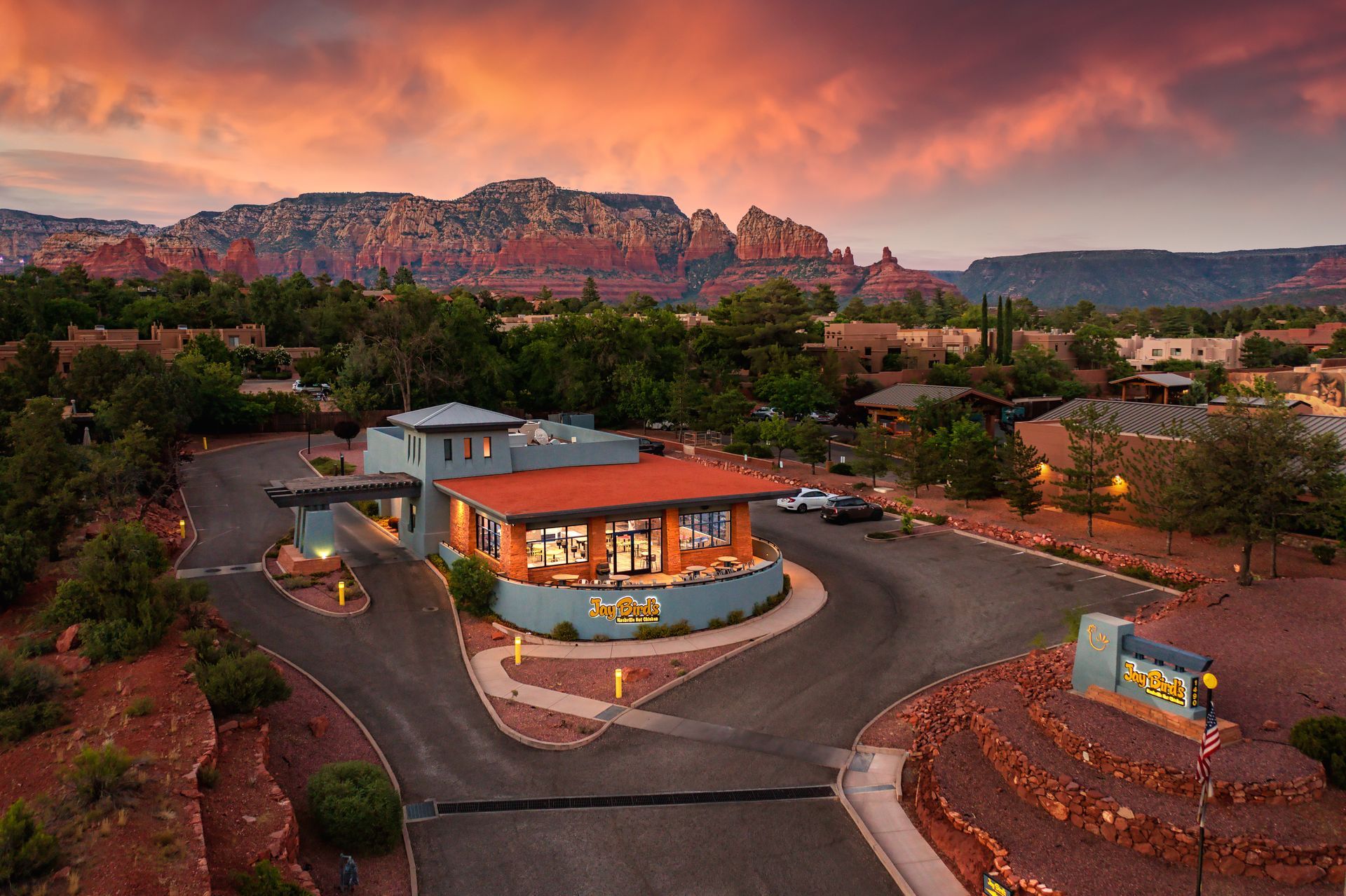 Building with red roof and large windows in Sedona, Arizona, at sunset, with red rock formations in the background.