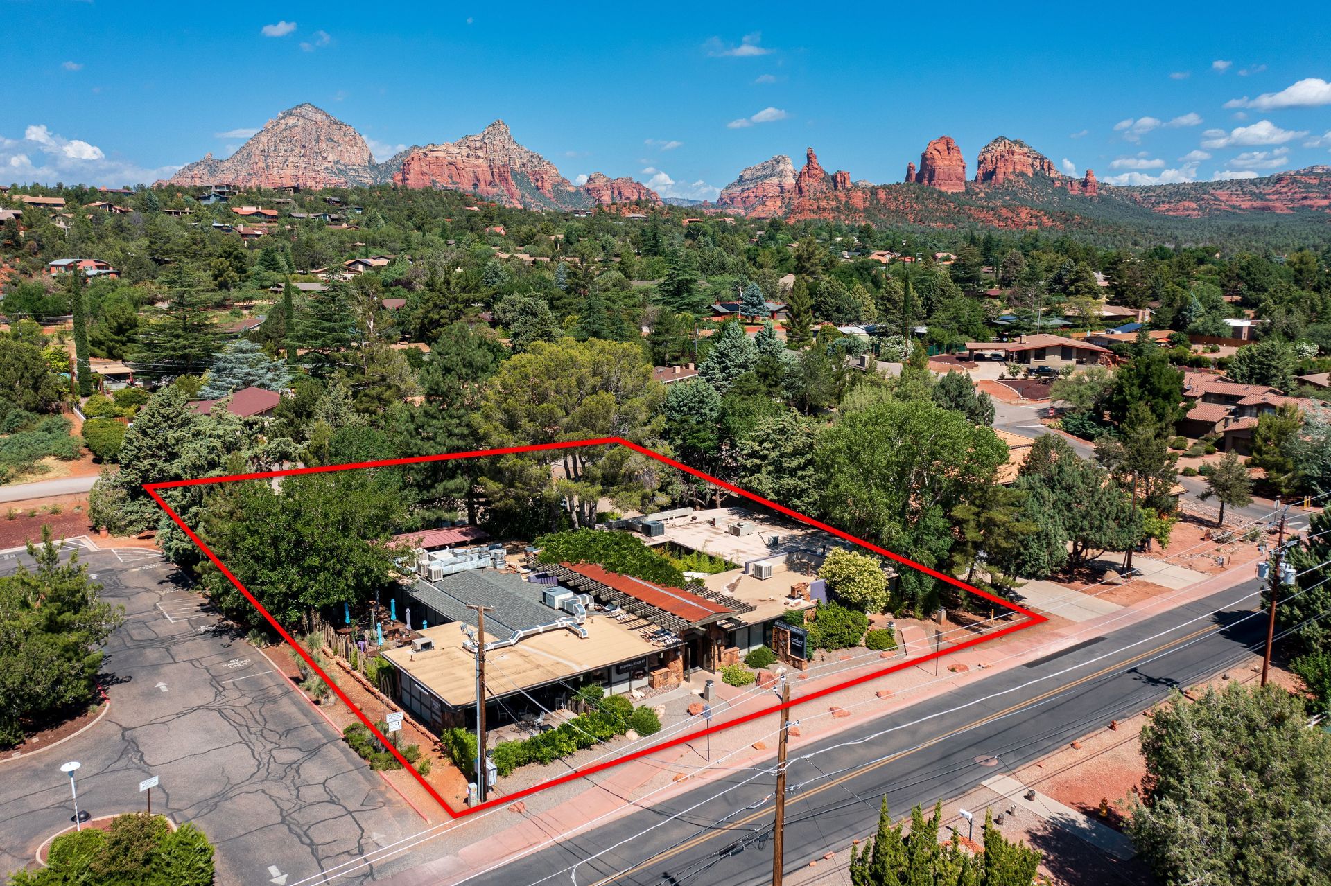 Aerial view of a commercial property in Sedona, Arizona. Red rock formations in the background. Marked with a red outline.