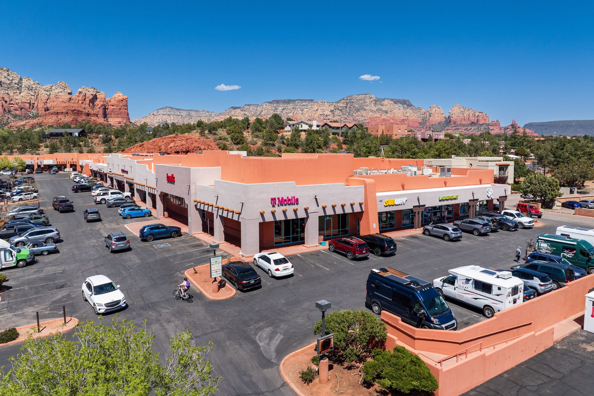 Shopping center in Sedona, Arizona, with red rock mountain backdrop. Cars parked in front of stores.