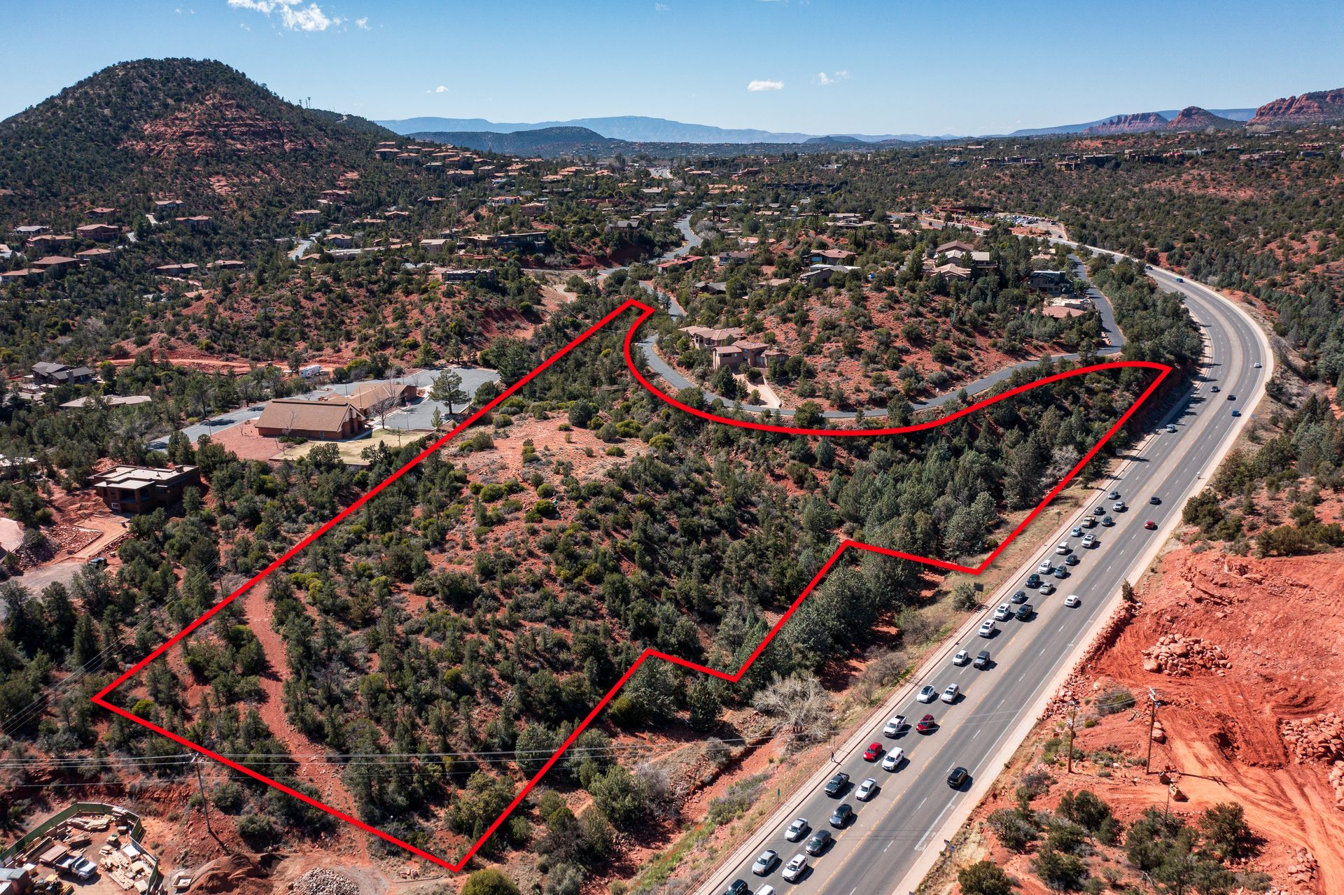 Aerial view of undeveloped land outlined in red near a highway in Sedona, Arizona.