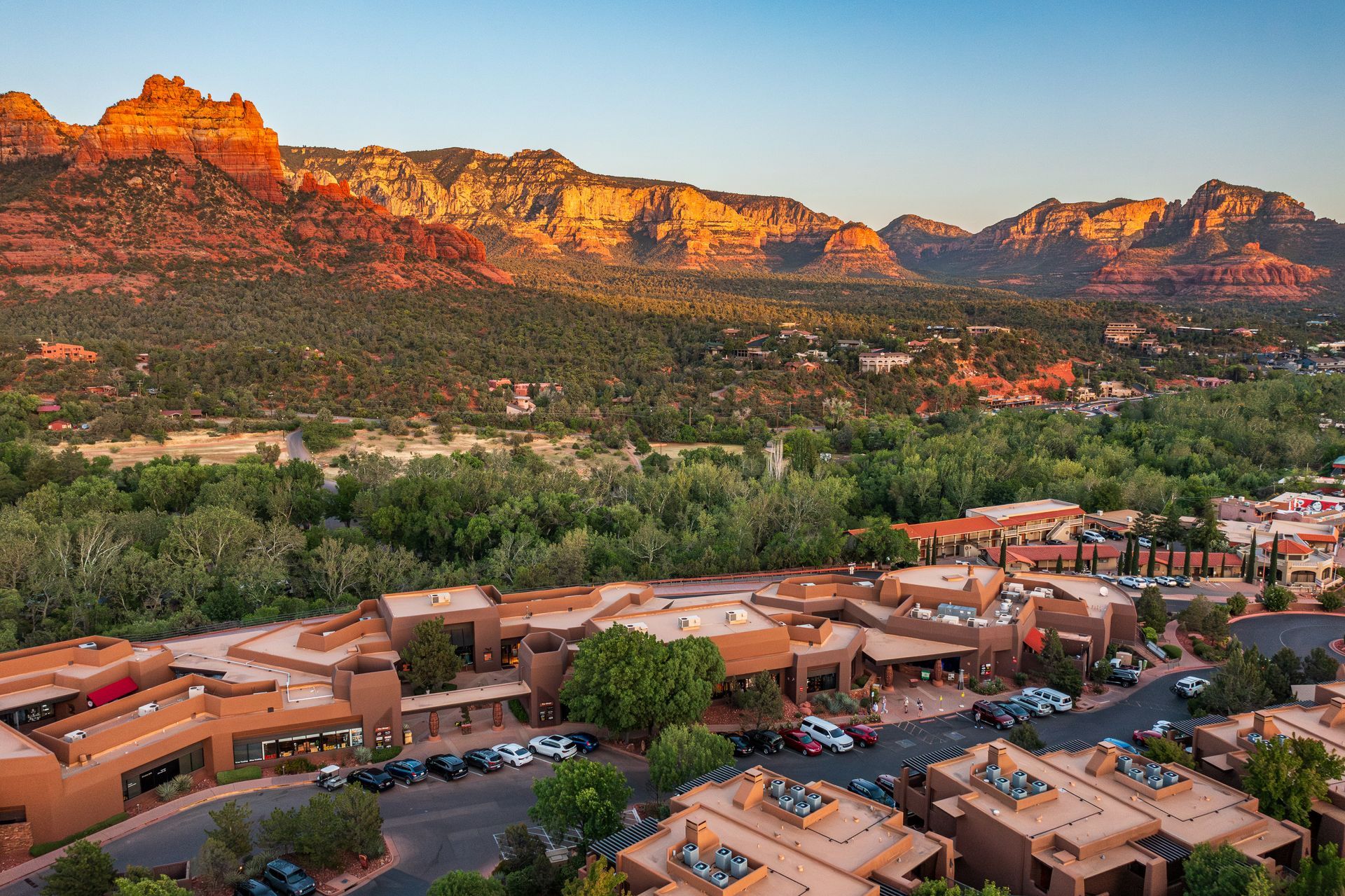 Sedona, Arizona landscape with red rock mountains and adobe-style buildings. Green trees in valley.