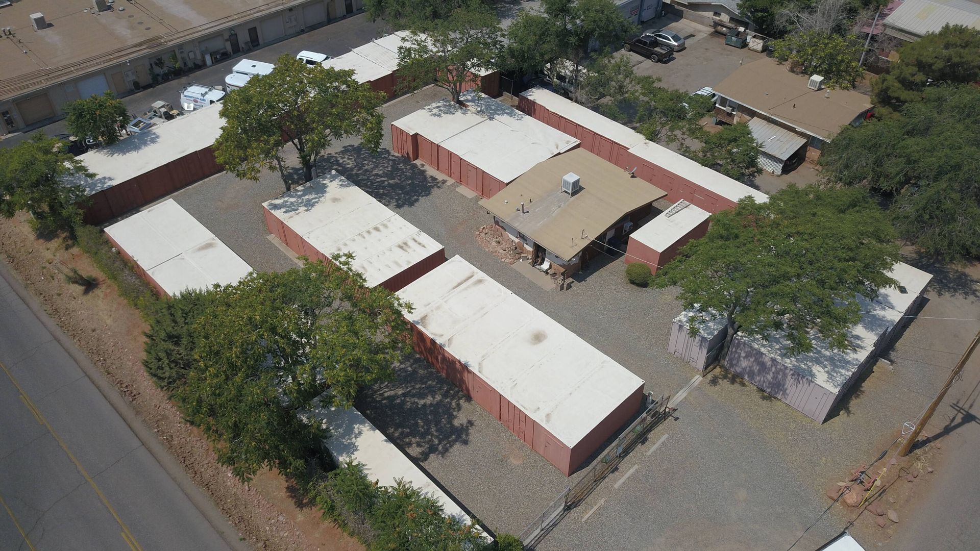 Aerial view of a storage facility with multiple units, mostly reddish brown, and a small central building.
