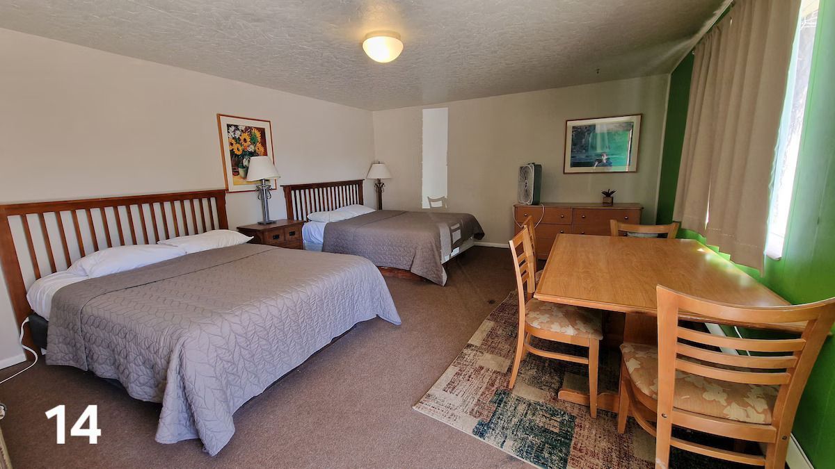 A hotel room with two beds , a table and chairs.