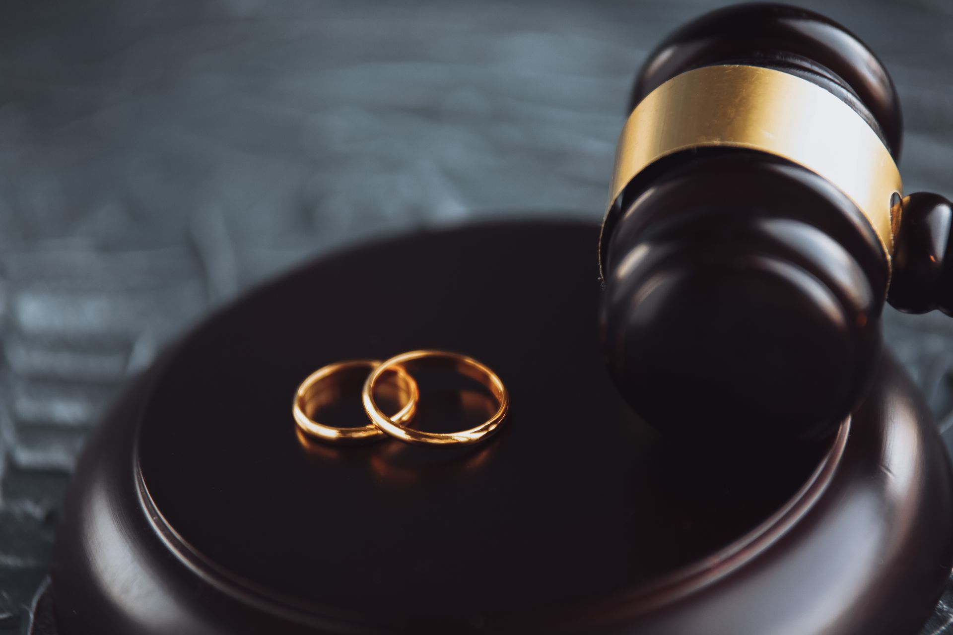 A pair of wedding rings are sitting on top of a judge's gavel.