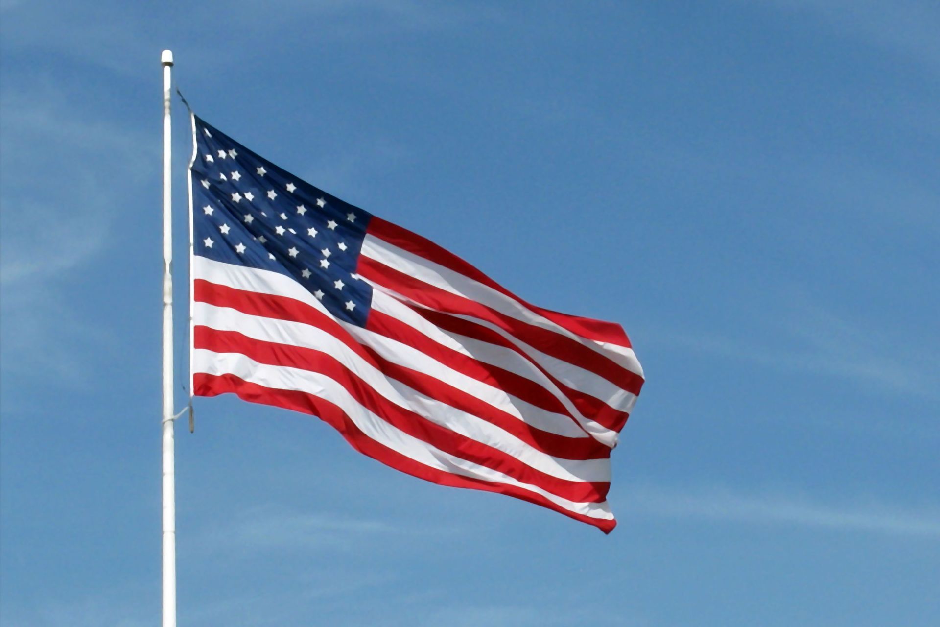 An american flag is waving in the wind against a blue sky