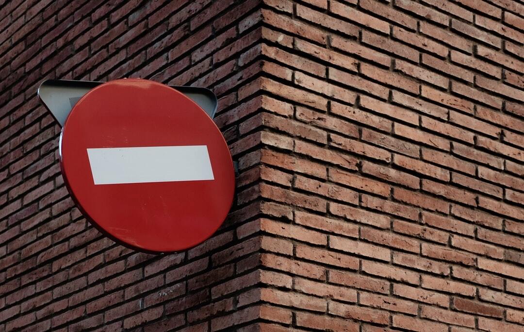Red do-not-enter traffic sign mounted on a brick building corner