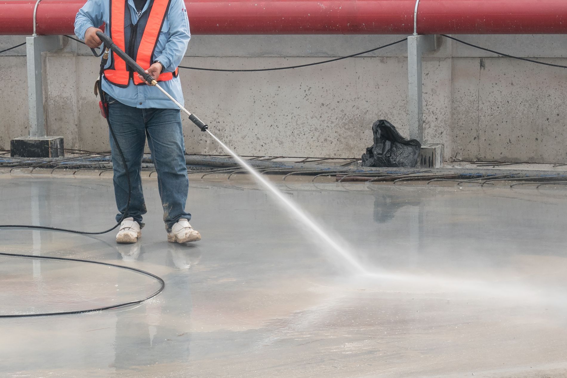 Worker pressure washing roof concrete