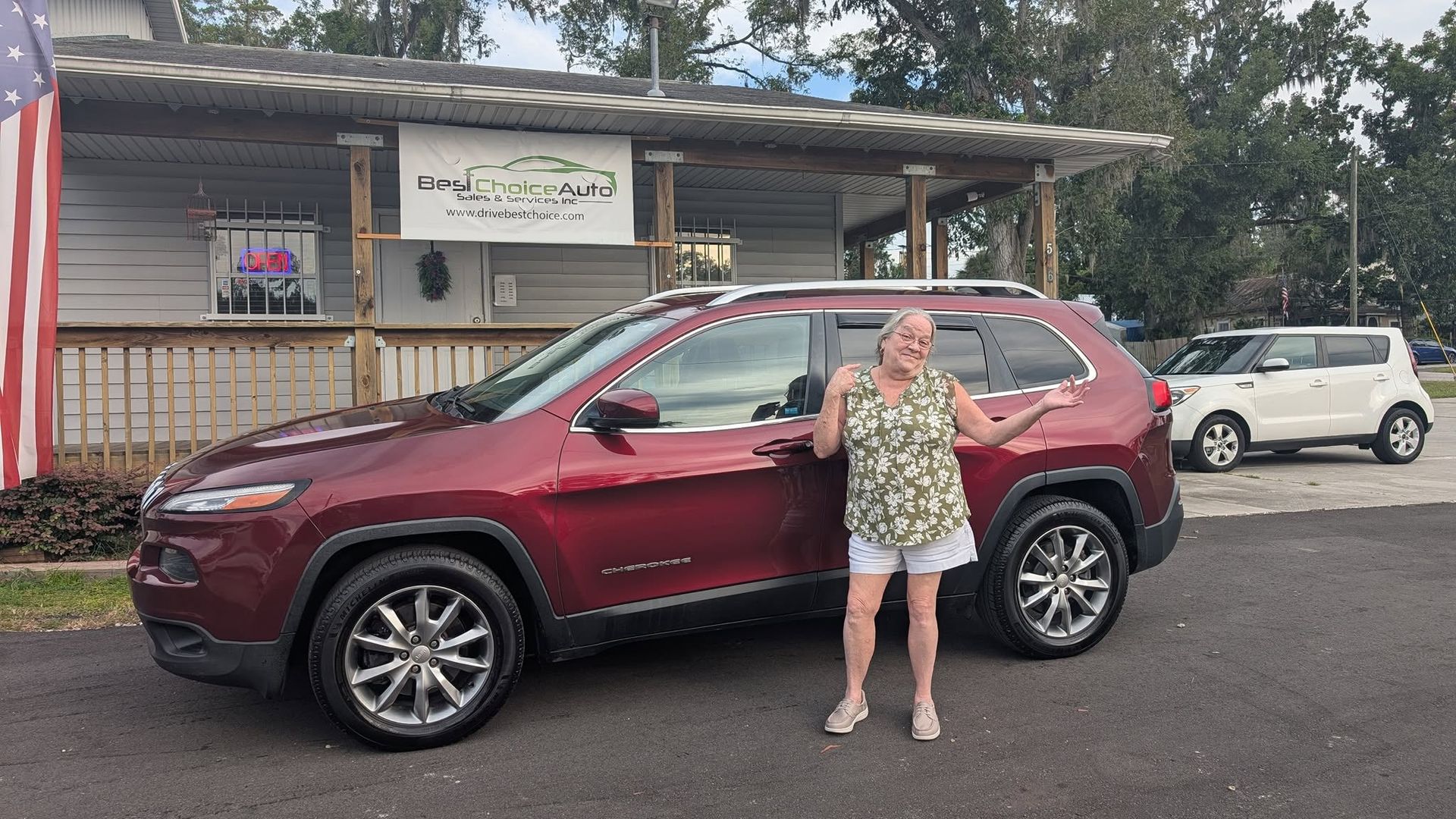Woman standing beside a maroon SUV parked in front of a building