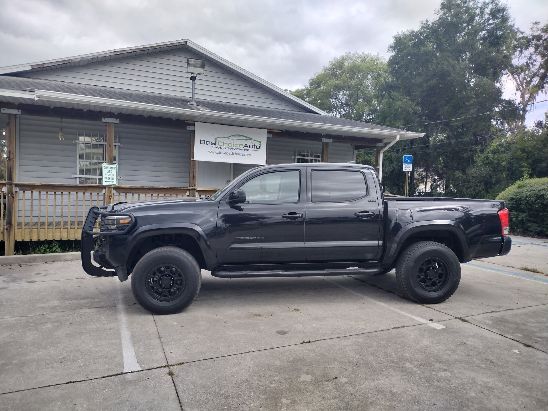 Black pickup truck parked in front of a small building on a concrete lot
