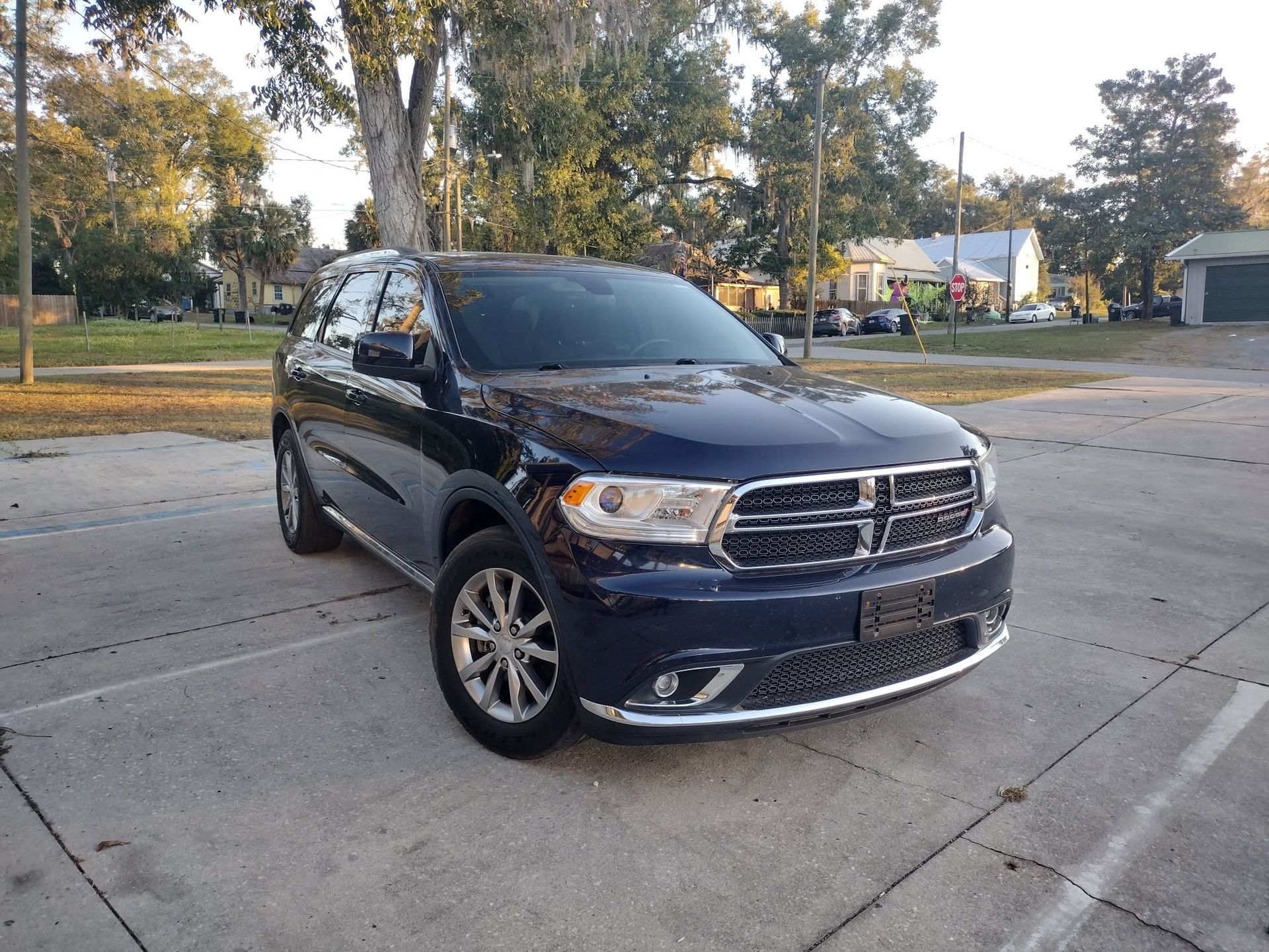 Black SUV parked on a concrete lot with trees and houses in the background