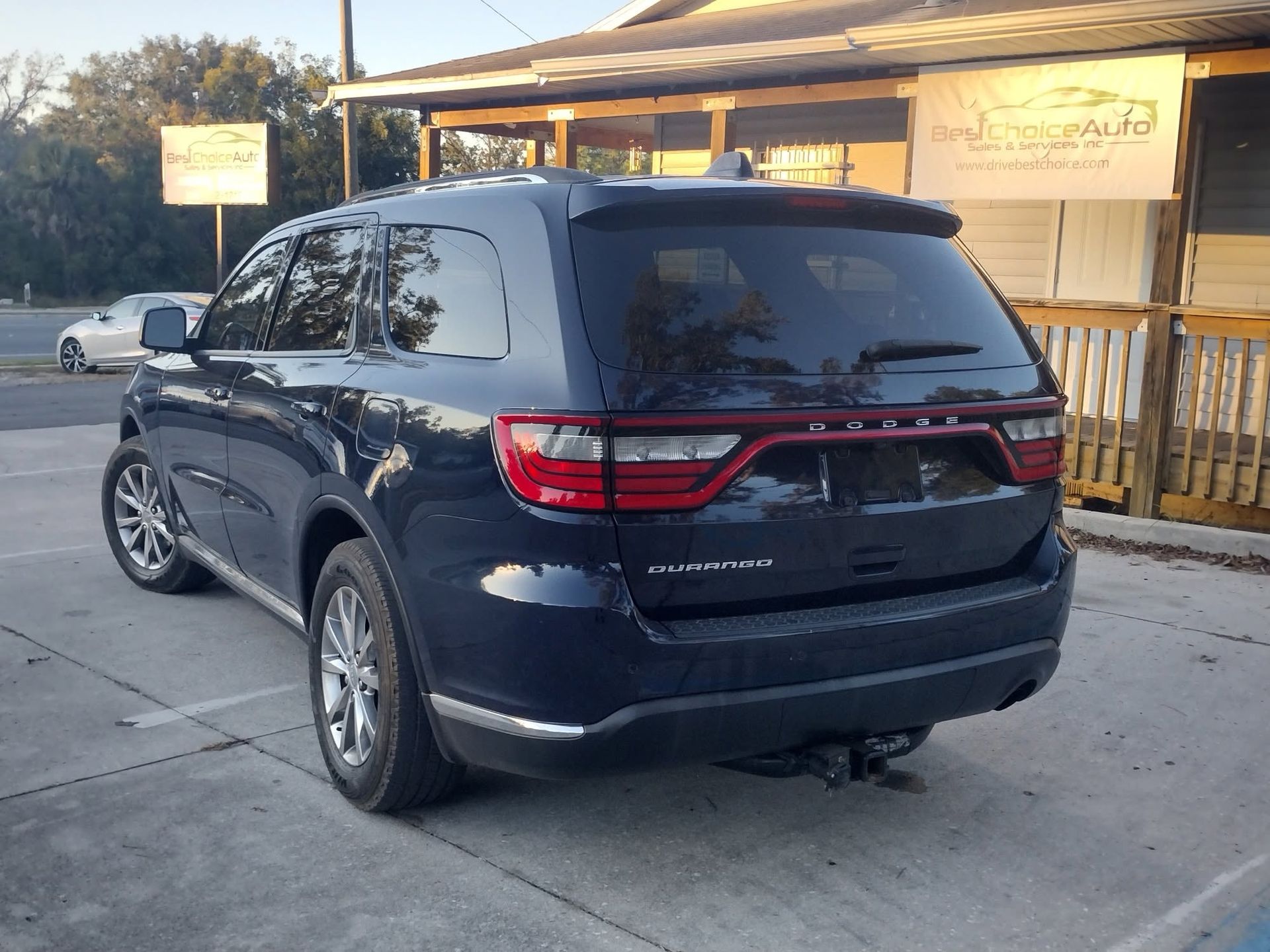 Dark blue minivan parked outside a storefront with a wooden porch.