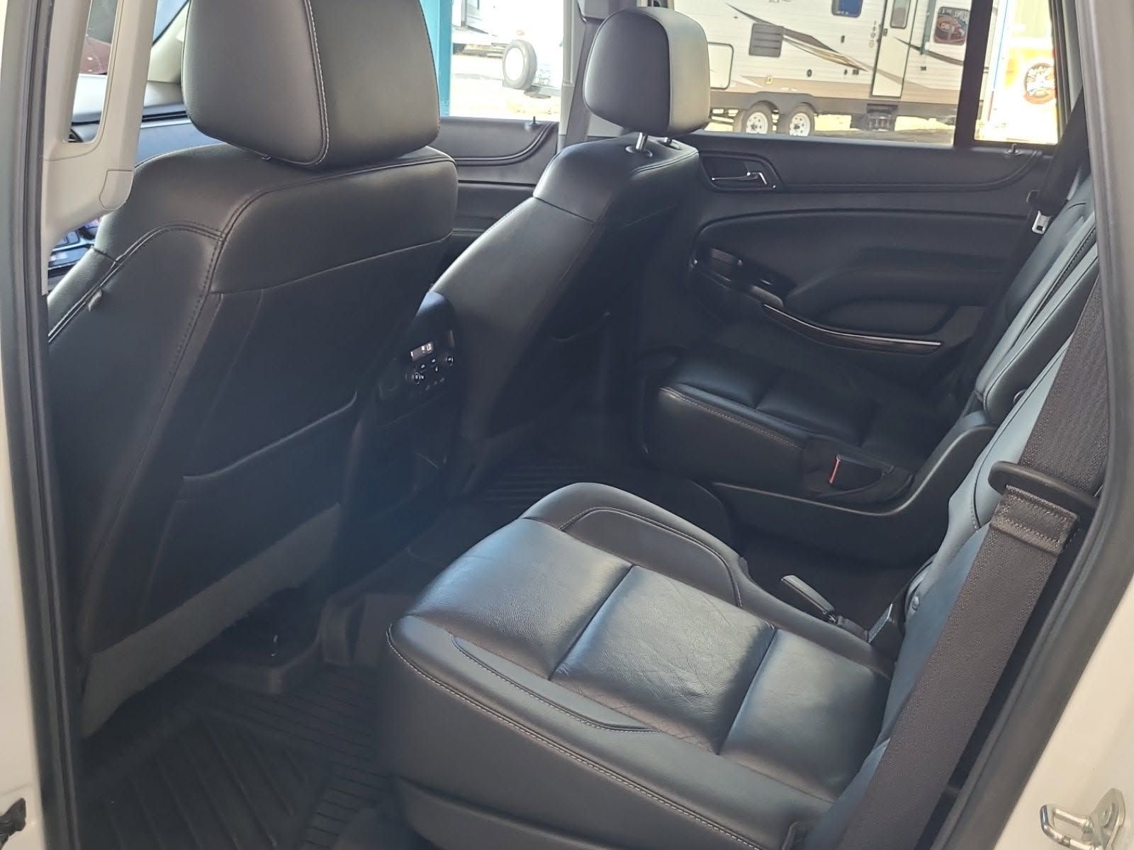 Car interior with black leather rear seats and folded center armrest, viewed from the back door