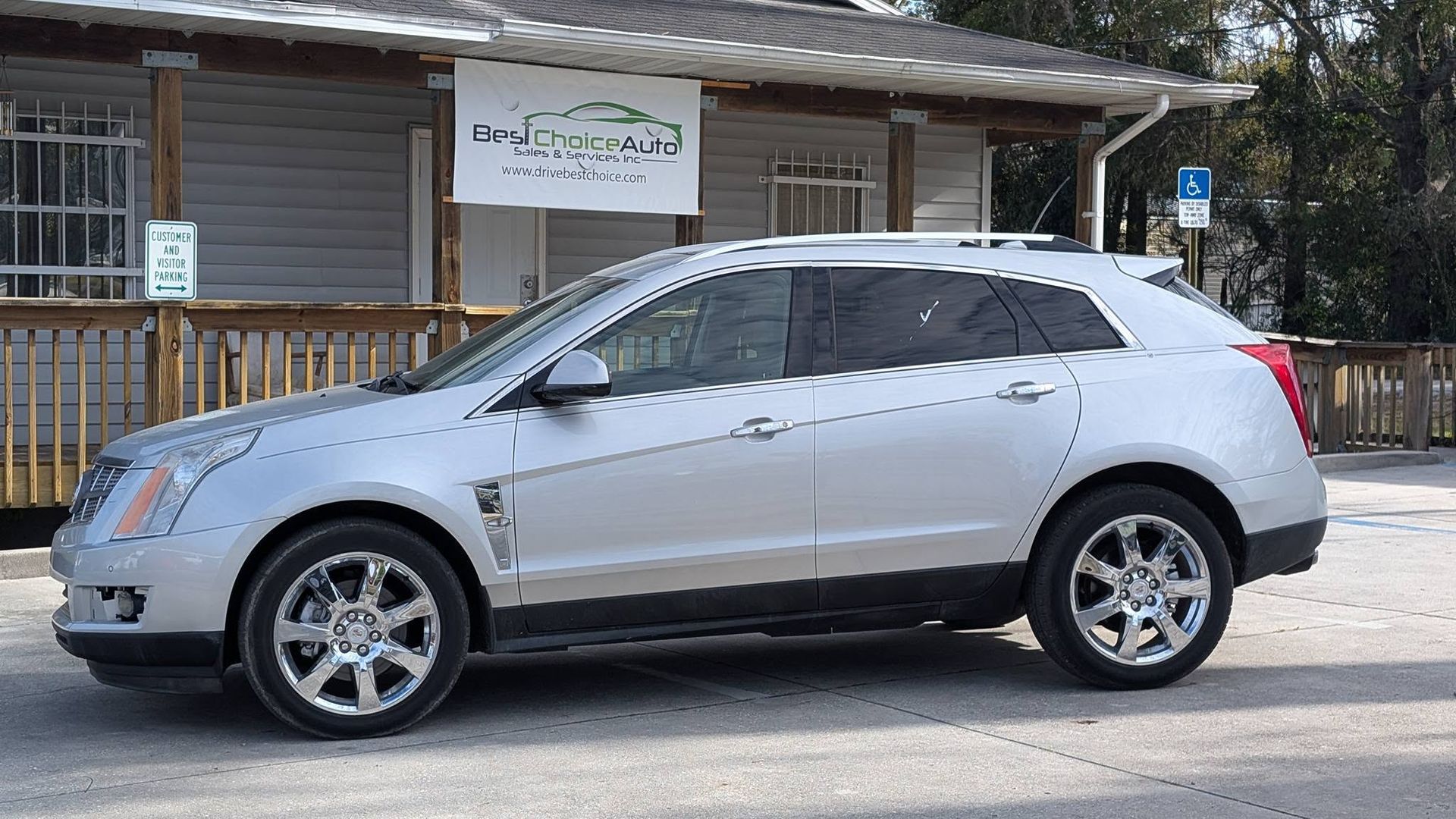 Silver SUV parked on a street in front of a rustic wooden building with a porch.