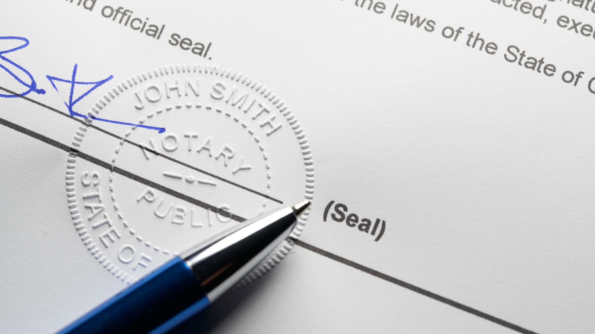 Pen signing a legal document beside an embossed seal stamp