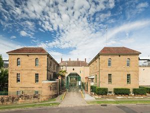 A large brick building with a driveway leading to it on a sunny day.