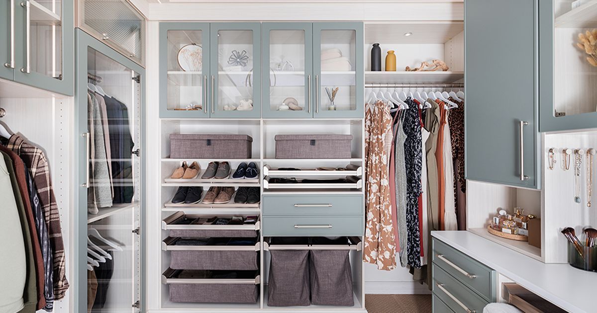 Walk-in closet with light blue cabinets, white shelves, hanging clothes, and storage bins.