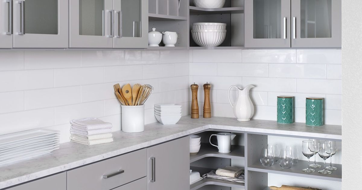 Modern white kitchen with gray cabinets, white tile backsplash, and neatly arranged countertop decor