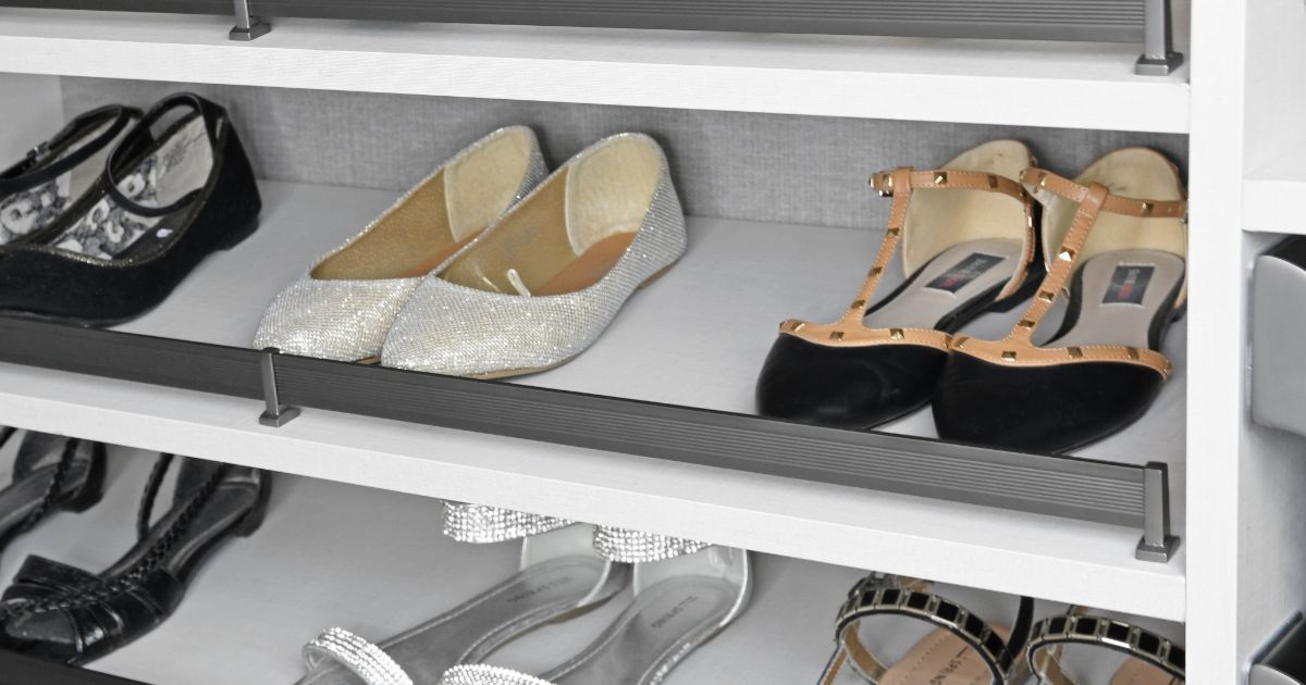 Shoes neatly arranged on a pull-out shoe rack inside a closet.