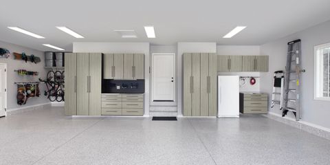 Spacious garage with beige cabinets, white appliances, shelves, and a ladder against the wall