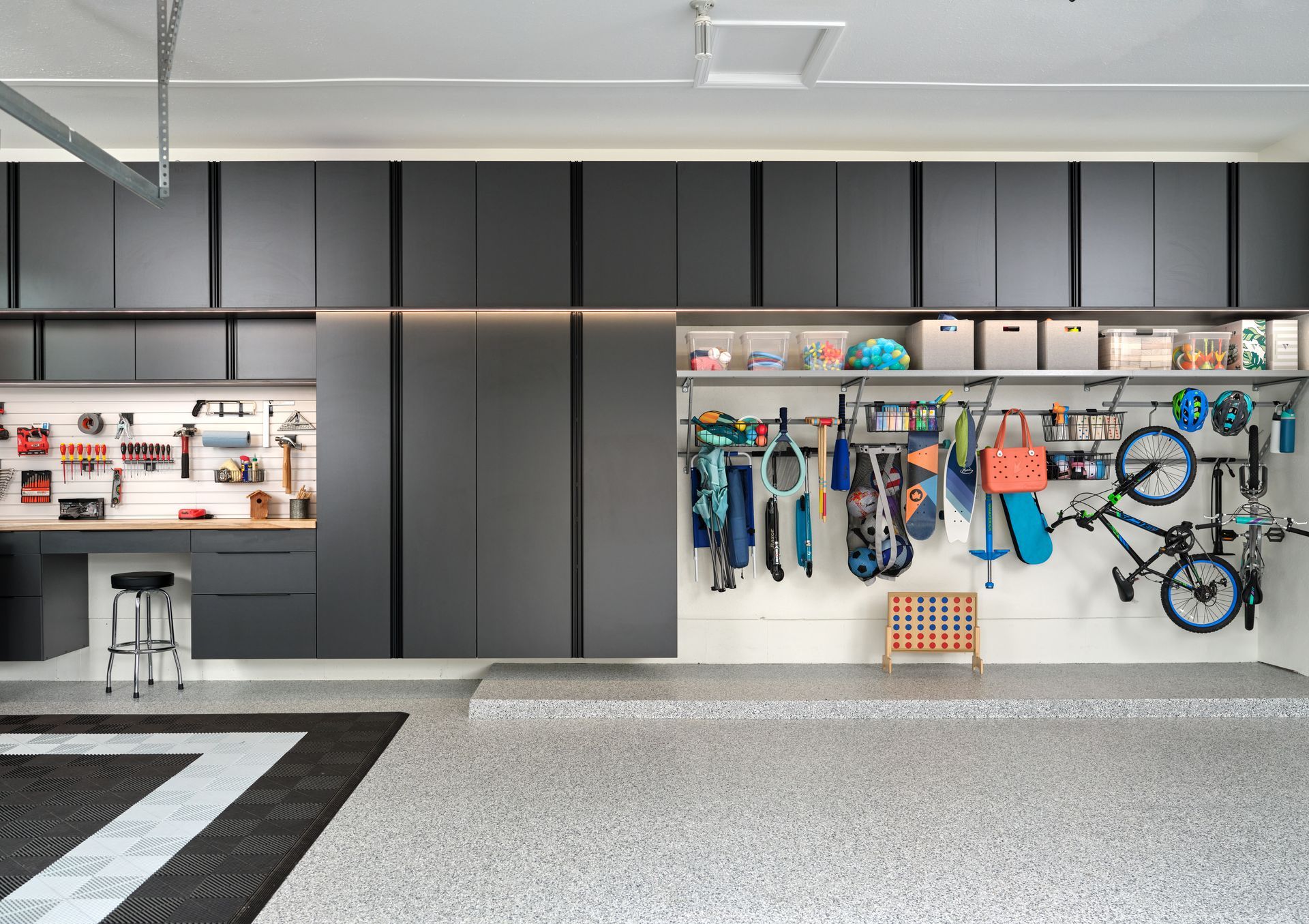Modern garage with wall-mounted tools, hanging bikes, and storage shelves on a gray floor