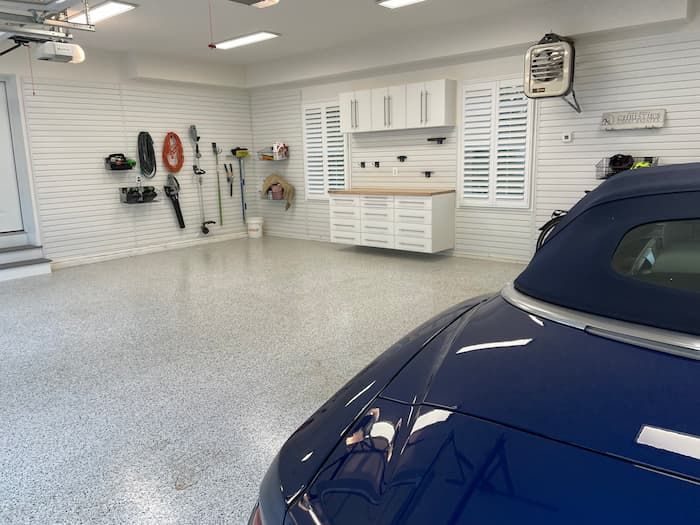 Interior of a clean garage with organized wall tools and a dark blue car in the foreground