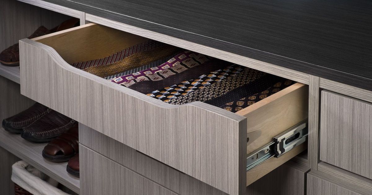 Open drawer in a gray cabinet showing neatly arranged ties and shoes underneath